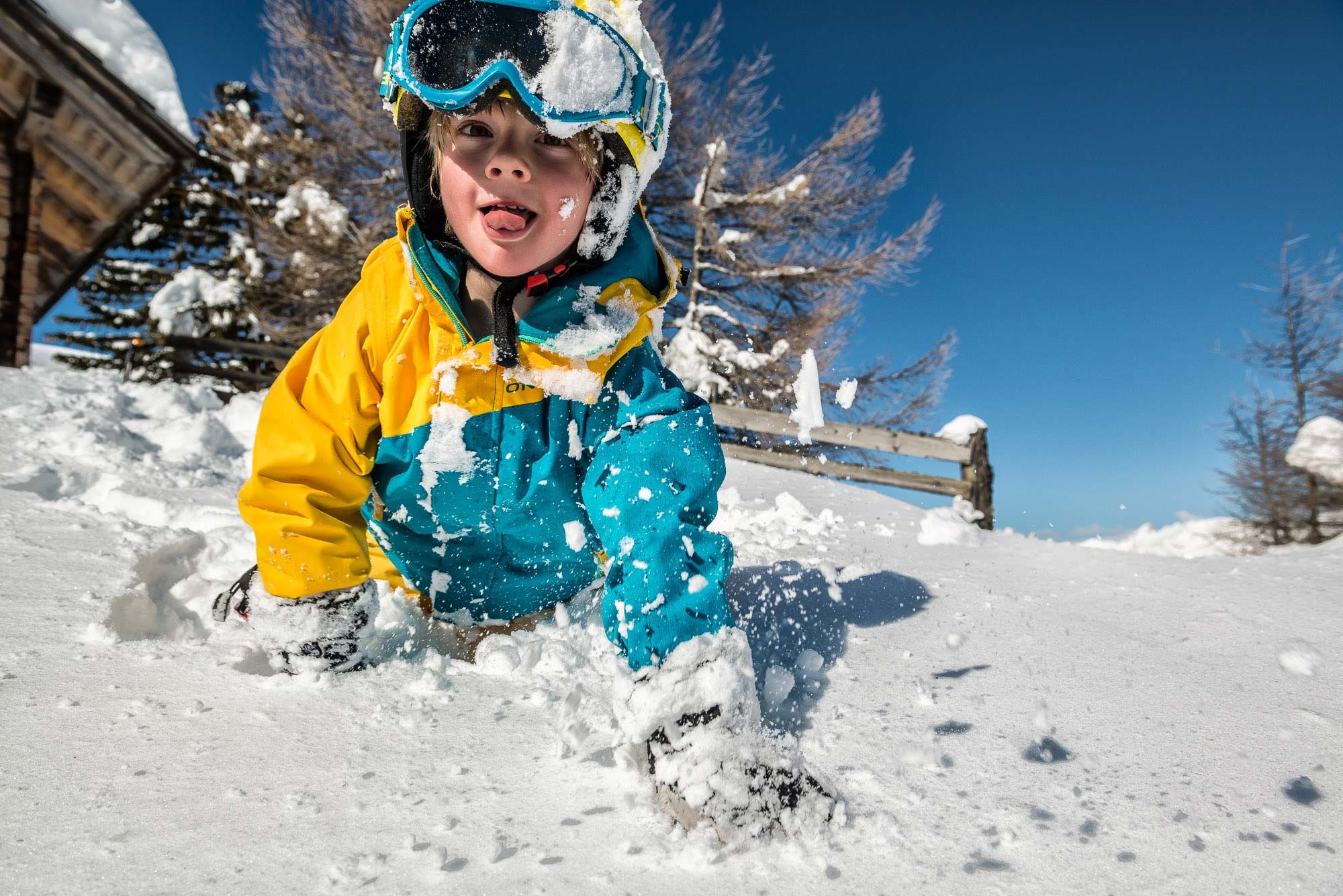 Ein Kind in bunter Winterkleidung spielt fröhlich im Schnee in Katschberg